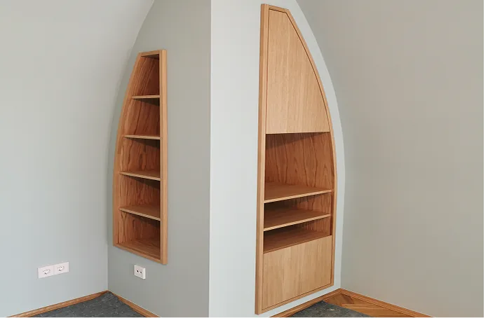 Eckregale aus Holz mit mehreren Fächern an einer hellgrauen Wand.