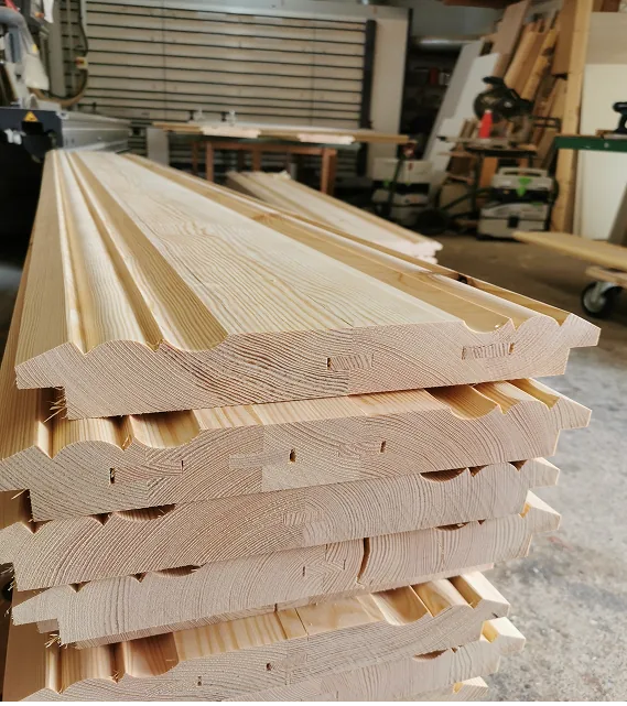 Gestapelte Profilholzplatten aus hellem Holz mit dekorativen Kanten in einer Werkstatt.