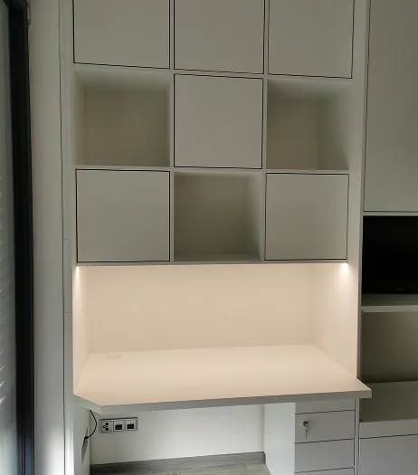 Weißer Schreibtisch mit eingebauten Schränken, Regalen und LED-Leuchten darunter.