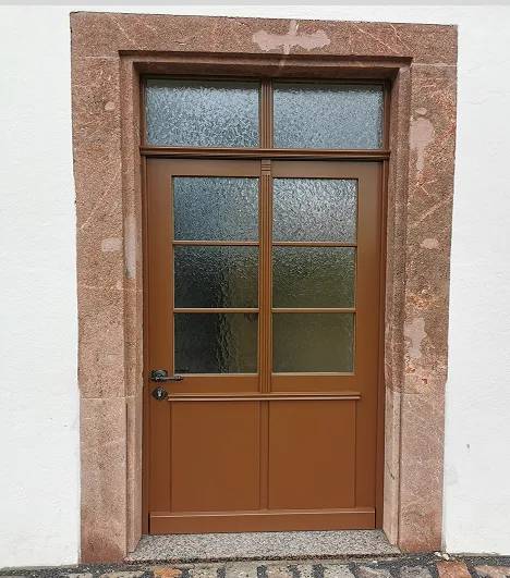 Braune Haustür mit Fenstern aus Milchglas und umgeben von rotem Steinrahmen.