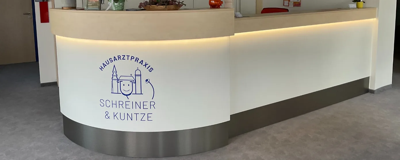Empfangstheke einer Arztpraxis mit dem Schriftzug Hausarztpraxis Schreiner & Kuntze und Logo.